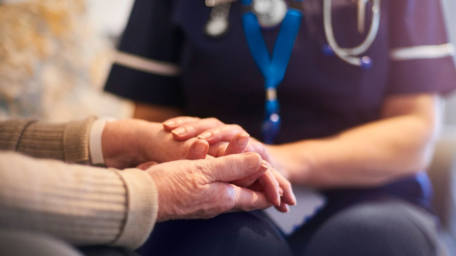 Image of a nurse holding an elderly patient's hands
