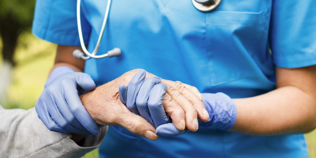 A nurse holding the hand of a nursing home resident.