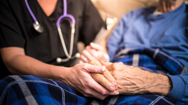 Photo of nurse holding elderly patient's hand