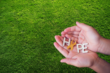 Photo of hands holding letters that spell the word "Hope." The "O" in "Hope" is a mental health awareness ribbon. 
